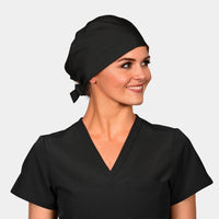 A woman wearing a solid black scrub hat and a black V-neck scrub top.