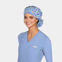 Person wearing a blue scrub top and bouffant floral scrub cap on a light gray background