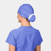 woman wearing a solid blue scrub cap and a blue scrub top on a light grey background