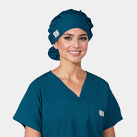 A woman wearing a Caribbean blue bouffant scrub hat and matching scrub top.