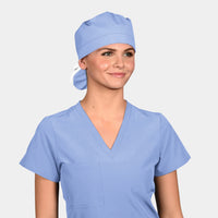 A person wearing a ceil blue scrub hat and matching scrubs, smiling against a white background.