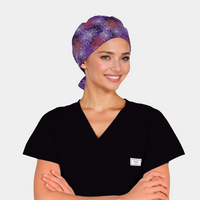 woman with a black scrub top on and a purple halloween scrub hat with spiderwebs on it