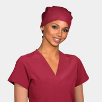 A woman wearing a solid color dark red pixie scrub hat and a matching scrub top.