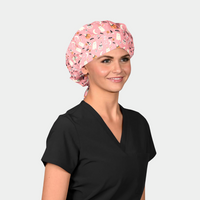 woman wearing a black scrub top and a pink halloween bouffant scrub hat that has ghosts, skeletons and pumpkins on it
