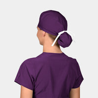 A person wearing a purple scrub hat tied in a ponytail at the back.