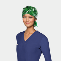 woman wearing a christmas scrub hat with green fir branches on a white background and also wearing a navy longsleeved scrub top