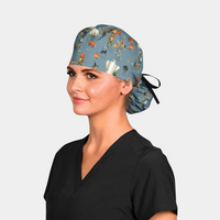 woman wearing a black scrub top and a halloween ponytail scrub cap that is blue with ghosts, cats and pumpkins on it