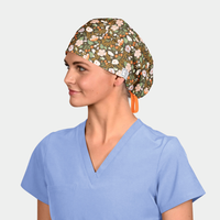 woman wearing a light blue scrub top and a scrub cap that is a brown floral with an orange ribbon