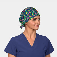 Woman wearing a colorful patterned scrub cap and blue scrub top on a light gray background