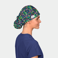 Person wearing a colorful scrub cap and navy scrubs on a light gray background