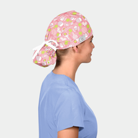 Person wearing a pink scrub cap with pickleball-themed design on a plain background