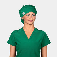 A person wearing a Pine Green bouffant scrub hat and matching green scrub top.