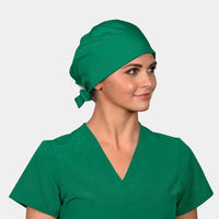 A person wearing a pine green scrub hat and matching medical scrub uniform.