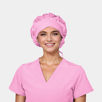 A person wearing a pink bouffant scrub hat and matching pink v-neck scrub top.
