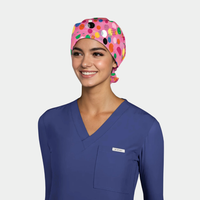 Person wearing a colorful polka dot scrub cap and blue scrub top on a light gray background