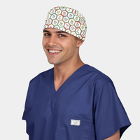 Man wearing a navy blue scrub set with a scrub cap that has the periodic table on it on a white background