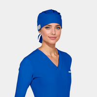 Woman wearing a blue scrub top and matching scrub cap on a light gray background