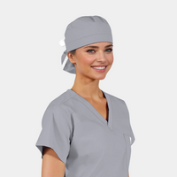 Woman wearing a gray scrub top and matching solid grey surgical cap on a white background