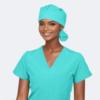 woman wearing a green ponytail scrub hat and a solid green scrub top on a light grey background.