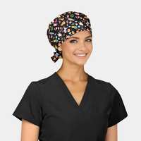 woman wearing a black scrub top and a christmas scrub hat that is black with toys on it on a white background