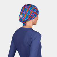 woman wearing a scrub hat with an blue, orange and pink abstract pattern a navy blue scrub top on a white background
