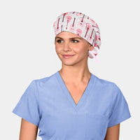 woman wearing a surgical hat with pink guitars on it and a light blue scrub top on a white background