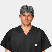 man with a black scrub top on and a mens halloween scrub hat with a pattern of white spiderwebs on a black background