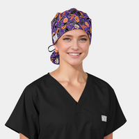 Person wearing a black scrub top and a Halloween-themed scrub cap on a light gray background