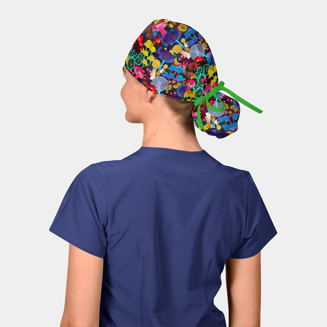woman wearing a navy blue scrub top and a scrub hat with mushrooms on it and a green ribbon