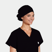 Woman wearing a black scrub top and a solid black scrub cap on a white background