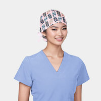 woman wearing a light blue scrub top and a scrub hat that is pink with blue cowboy boots on it
