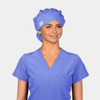 Woman wearing a blue scrub top and matching bouffant scrub cap on a light gray background