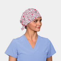 woman wearing a breast cancer themed scrub hat that is pink with black words and red hearts on it