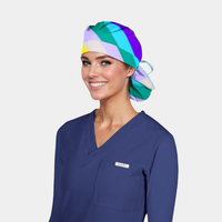 Person wearing a colorful scrub cap and navy blue scrub top on a light gray background