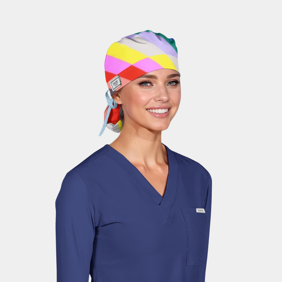 Person wearing a colorful scrub cap and blue scrub top on a light gray background