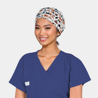 woman with an animal themed scrub cap on with various cats all over it and also wearing a navy scrub top