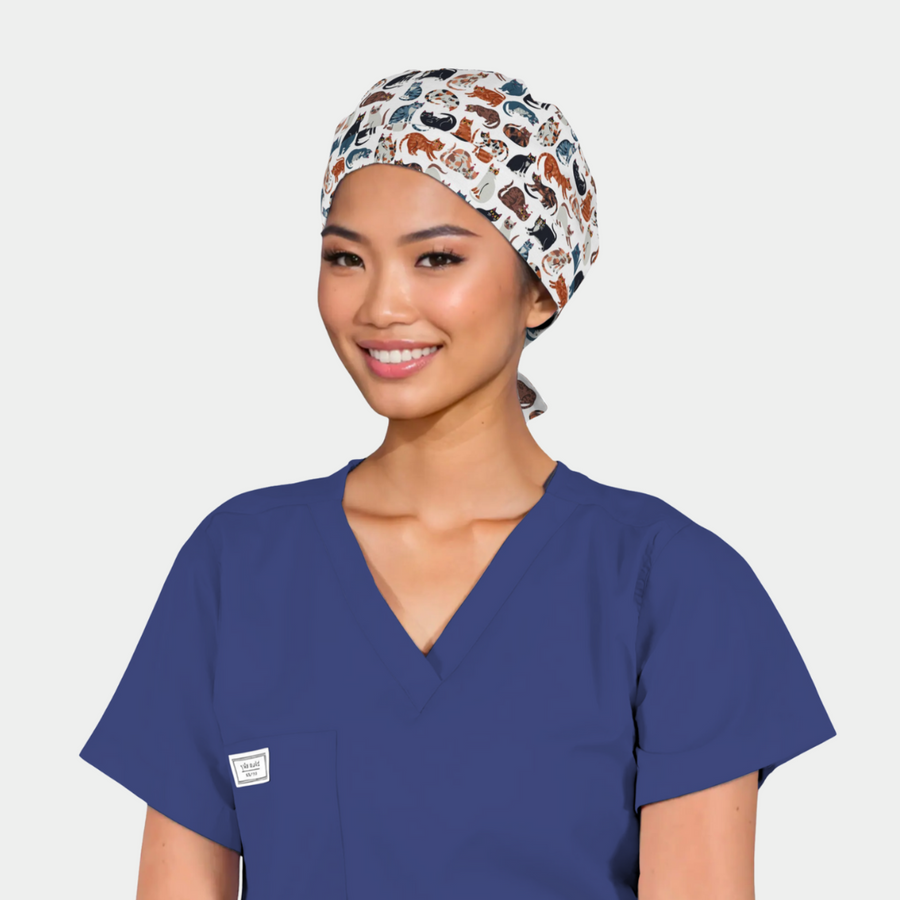 woman with an animal themed scrub cap on with various cats all over it and also wearing a navy scrub top
