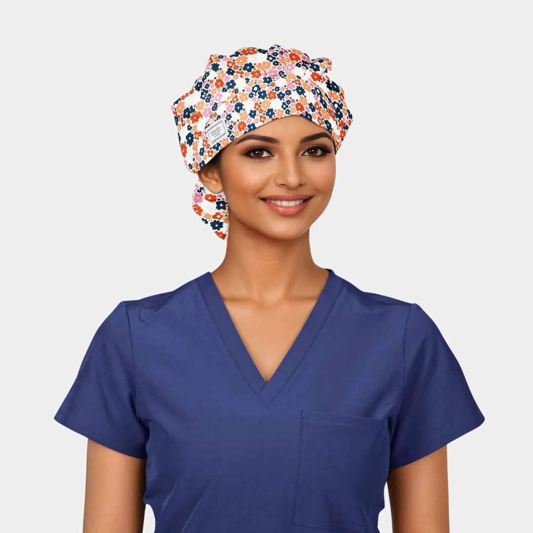 woman wearing a floral bouffant scrub hat with small navy, orange and red flowers and a navy blue scrub top