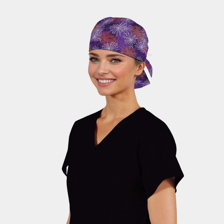 Woman wearing a black scrub top and a purple patterned scrub cap with spiderwebs on it for halloween.