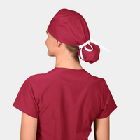 Person wearing a red scrub cap and shirt on a light gray background