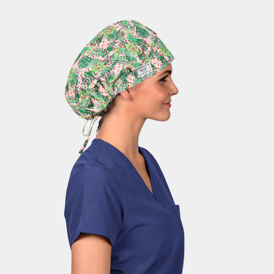 woman wearing a navy blue scrub top and a christmas bouffant scrub hat that is pink with green palms and christmas lights