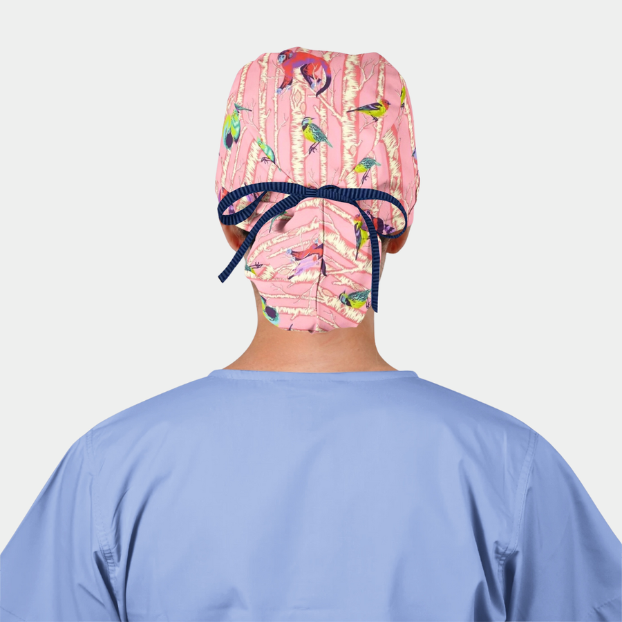 woman wearing a light blue scrub top and a pink ponytail scrub hat with a navy ribbon