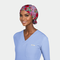Woman wearing a pink floral scrub hat and light blue scrub top on a white background