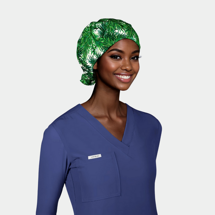 woman with a long sleeve navy scrub top on and a christmas surgical cap with green fir branches on a white background