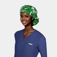woman wearing a navy blue scrub top and a bouffant scrub hat that is white with green fir branches on it