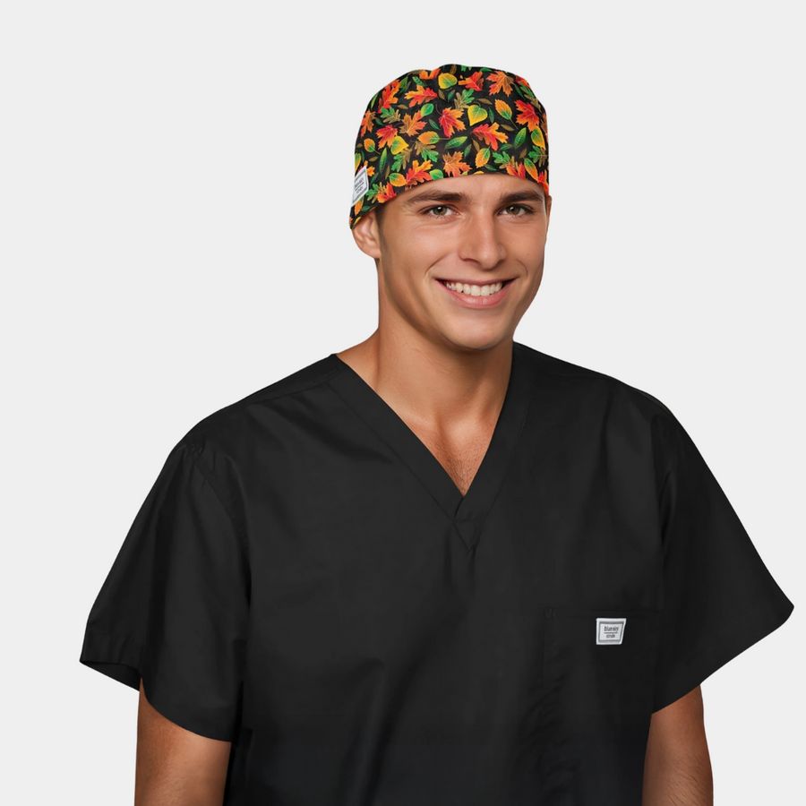 man wearing a black scrub top and a mens scrub hat with red, orange and green leaves on a black background