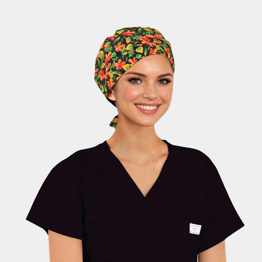 woman wearing a scrub hat with red, orange, yellow and green leaves on a black background and also wearing a black scrub top