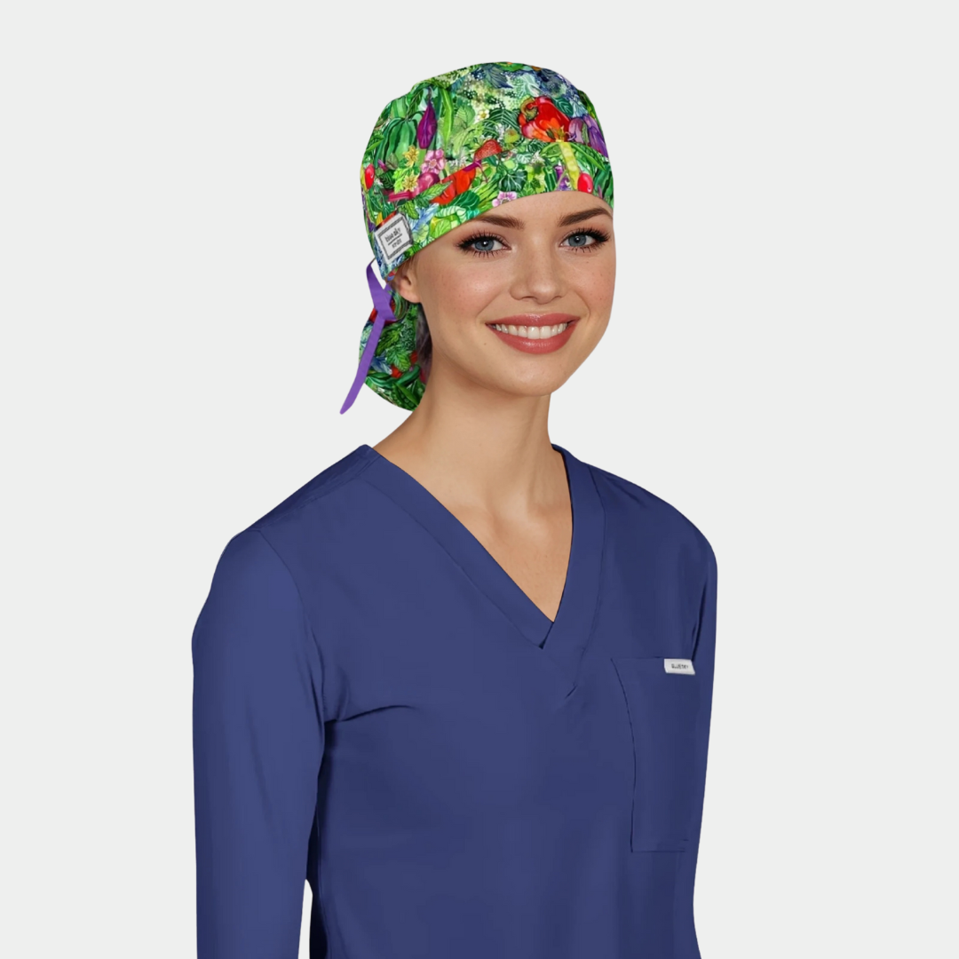 Person wearing a colorful scrub cap with vegetables and blue scrub top on a light gray background
