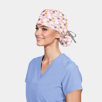 woman wearing a light blue scrub top and a pink ponytail scrub hat with cats on it