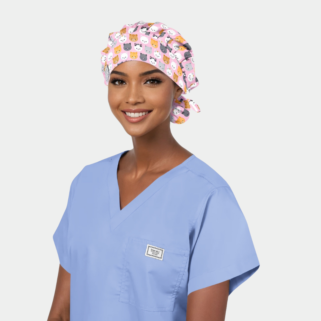 woman wearing a light blue scrup top and a pink bouffant scrub hat with cats on it
